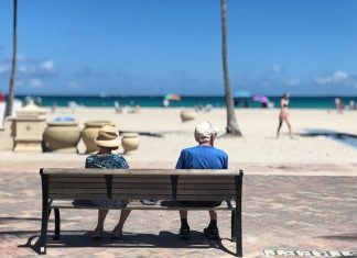 Helping Your Loved One to Have a Happy Retirement Old couple sitting by the beach enjoying the sun