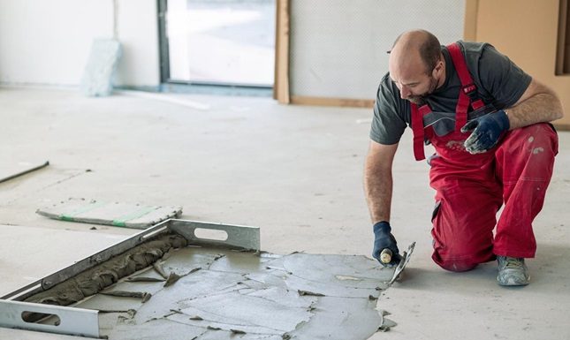 Why Durable Surfaces Are a Must for Harsh Climates A worker applies durable concrete flooring, essential for withstanding the harsh climates and heavy use in Canadian homes and buildings