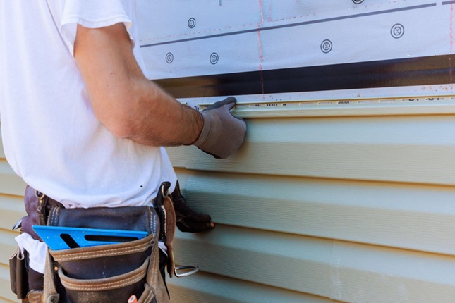 A worker installing commercial siding, ensuring durability in Calgary's climate challenges