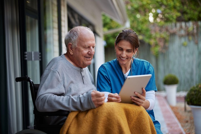 Caregiver and elderly patient reviewing documents on a tablet