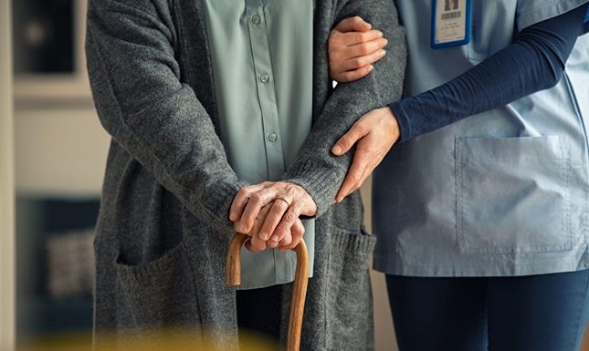Financial Planning for Long-Term Home Care Support Caregiver supporting an elderly person with a cane